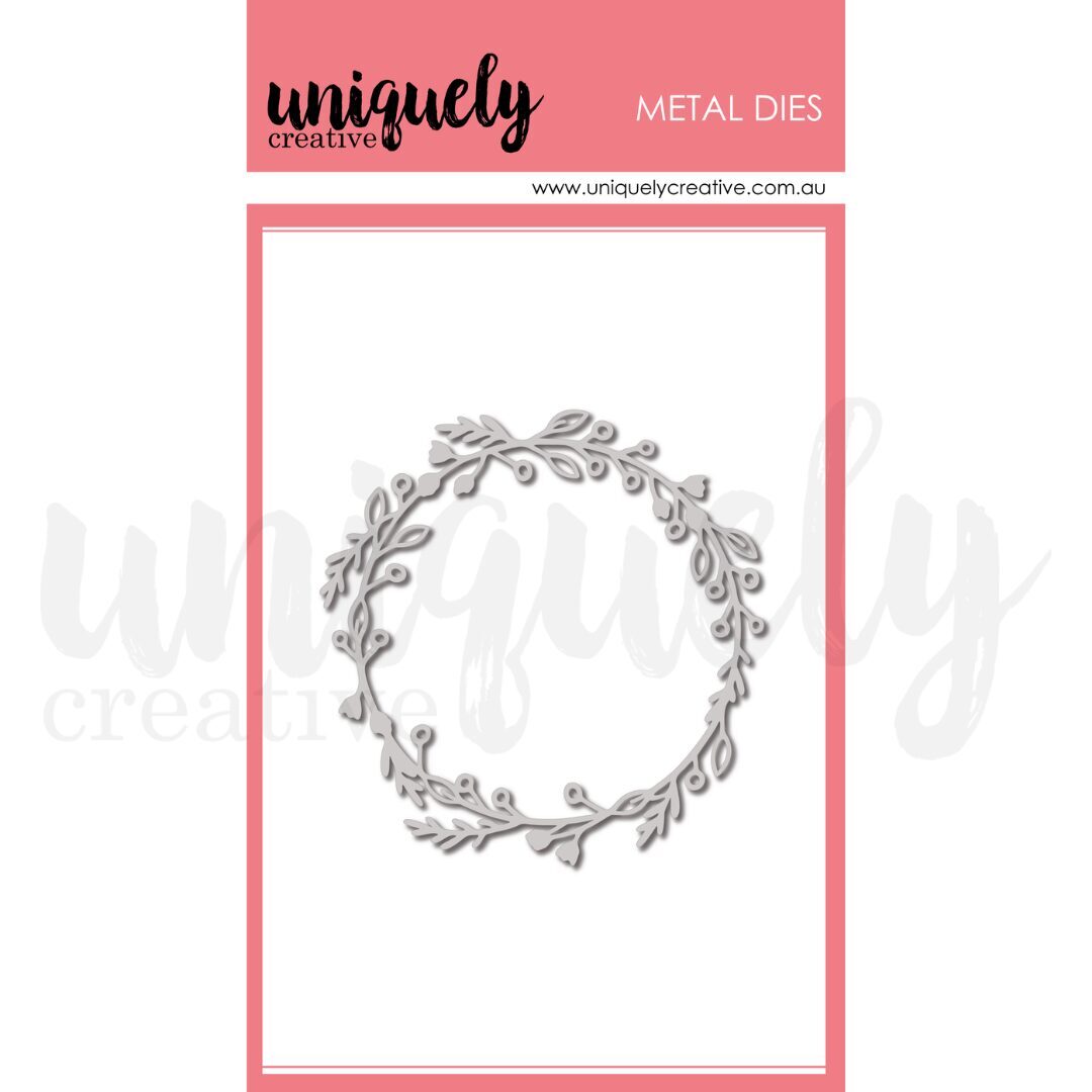 A single metal die cutout shown on a branded card. The die is a circular wreath-like border with leafy vines in a light gray/silver tone.